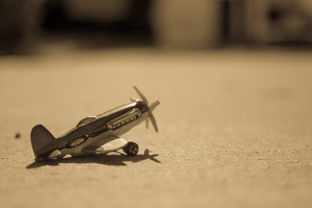 a tiny toy airplane sitting on the ground - the image is finished in sepia tone - photo (c) Victoria Klum / Victoria Klum Photography